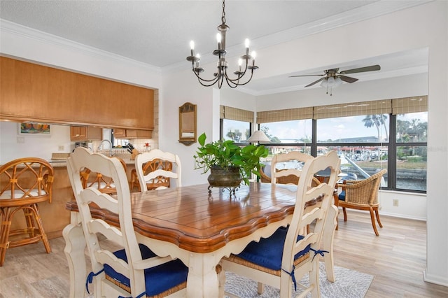 dining area with ceiling fan with notable chandelier, ornamental molding, light wood-type flooring, and baseboards