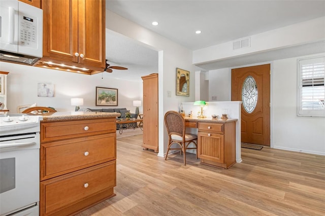 kitchen with white appliances, brown cabinetry, light wood-style flooring, and visible vents