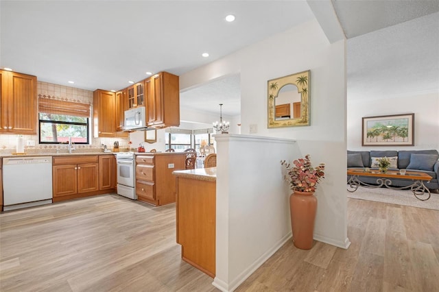 kitchen with a chandelier, white appliances, light wood-style floors, light countertops, and brown cabinets