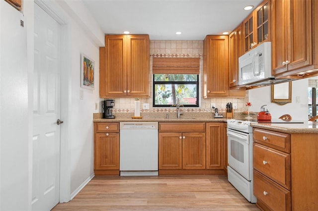 kitchen with light wood-style floors, white appliances, a sink, and tasteful backsplash