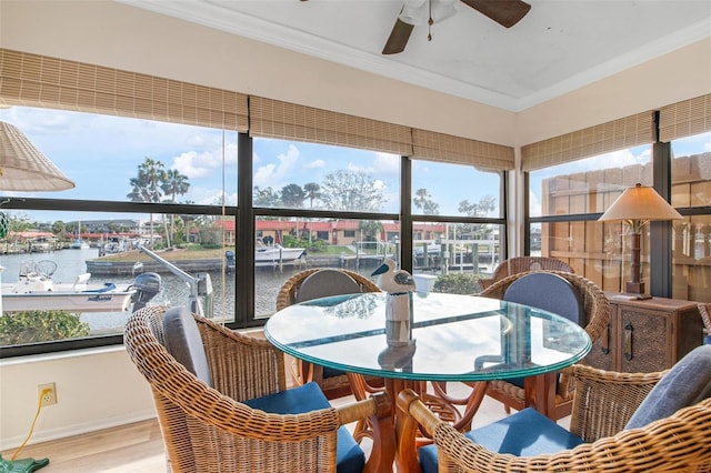 sunroom / solarium featuring ceiling fan and a water view