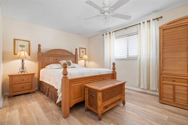 bedroom with light wood-type flooring, ceiling fan, baseboards, and a textured ceiling