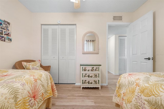 bedroom with a closet, light wood-type flooring, visible vents, and baseboards