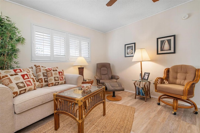 living area with ceiling fan, light wood-style flooring, and a textured ceiling