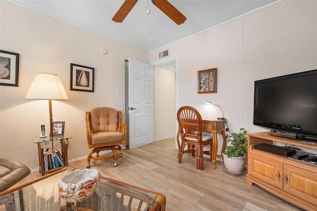 living room with ceiling fan, a textured ceiling, light wood-type flooring, and visible vents