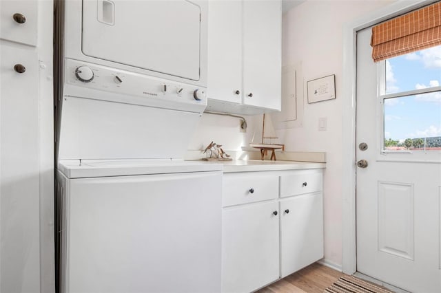 washroom featuring stacked washer / drying machine, laundry area, and light wood finished floors