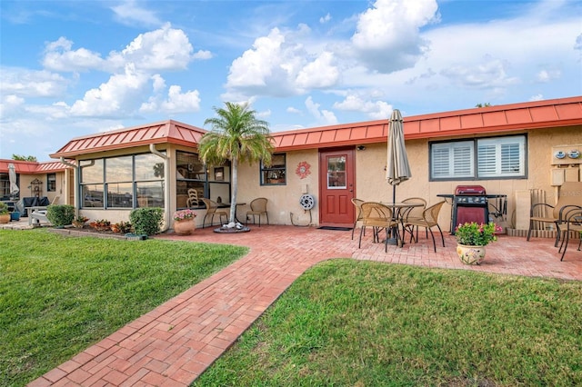 rear view of house with a lawn, a patio area, and stucco siding