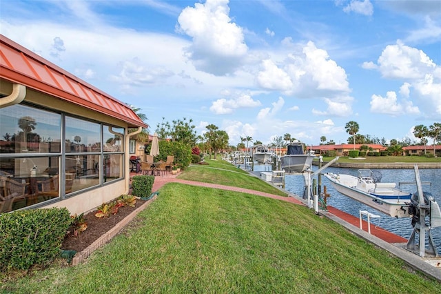 view of yard with a dock, a water view, and boat lift