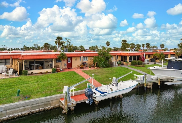 back of property with a water view, a yard, boat lift, and a patio