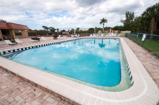 pool with a patio area and fence