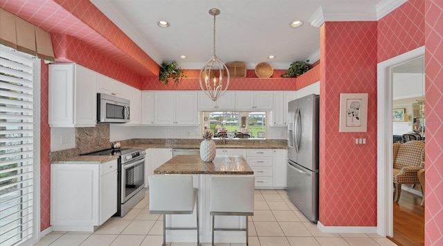 kitchen featuring white cabinets, wallpapered walls, ornamental molding, and stainless steel appliances