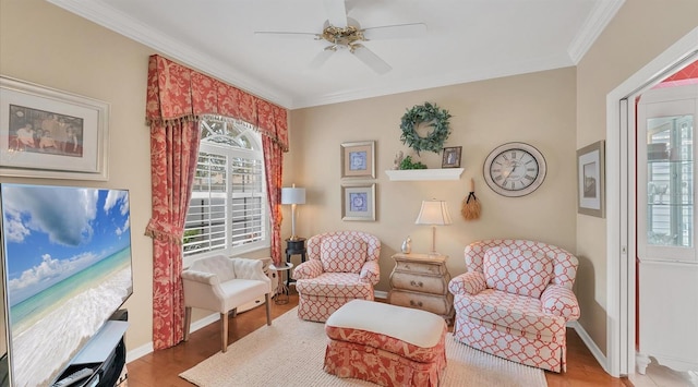 sitting room with a ceiling fan, baseboards, crown molding, and wood finished floors