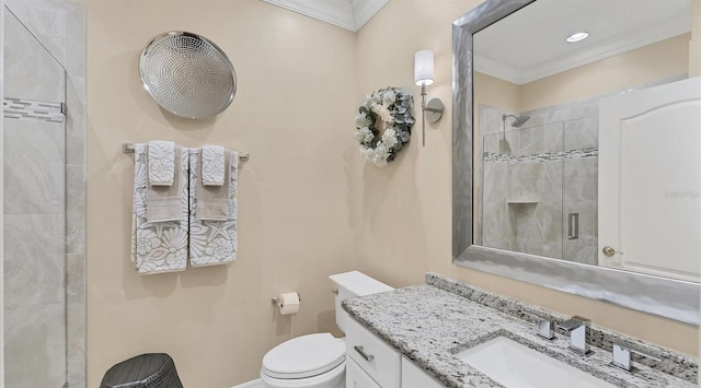 bathroom featuring vanity, a tile shower, toilet, and crown molding