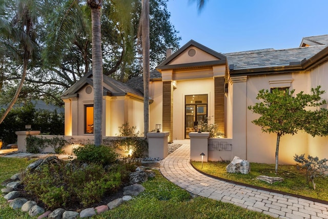 doorway to property featuring a chimney and stucco siding