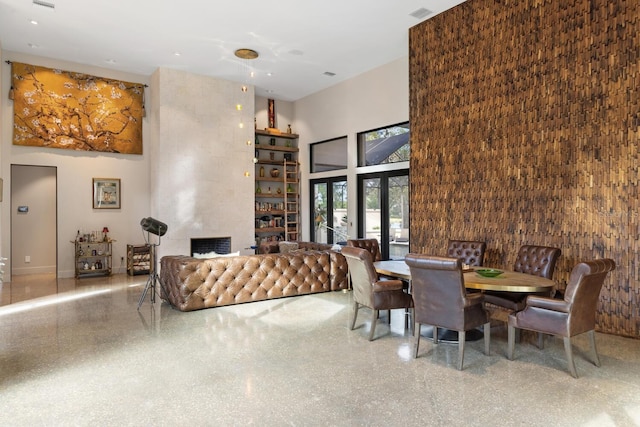 dining space featuring a fireplace, a high ceiling, and speckled floor