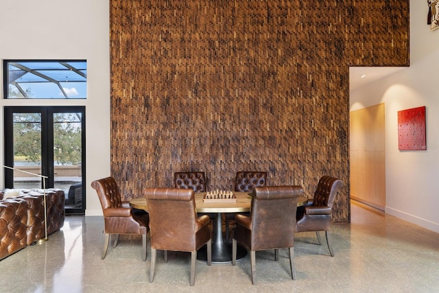 dining space with a towering ceiling, baseboards, french doors, and speckled floor