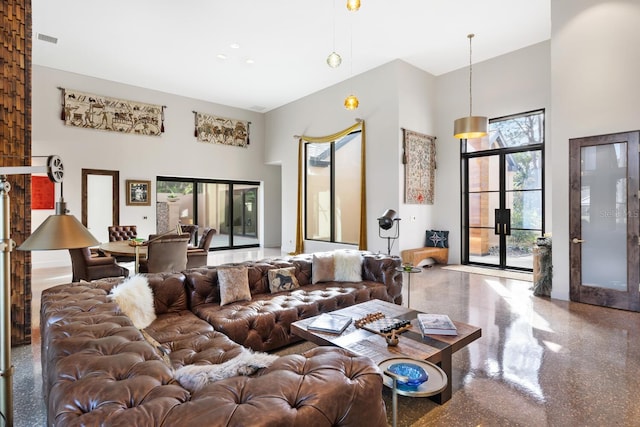 living room featuring visible vents, a towering ceiling, and speckled floor