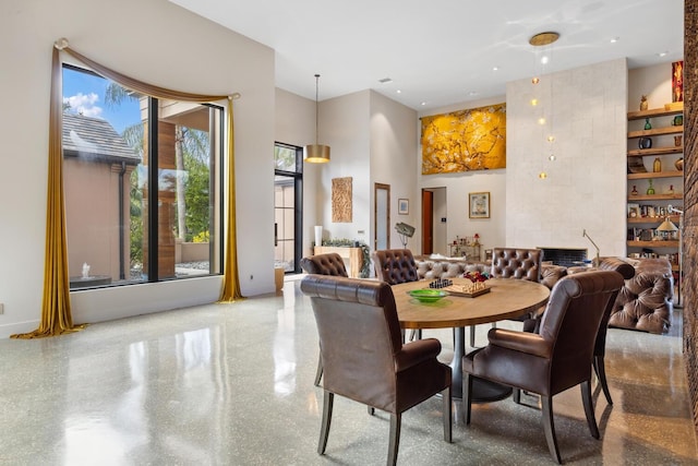 dining space with a tile fireplace and a high ceiling