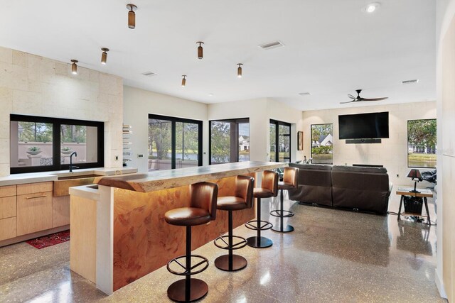 kitchen with visible vents, modern cabinets, a breakfast bar area, light brown cabinetry, and a sink