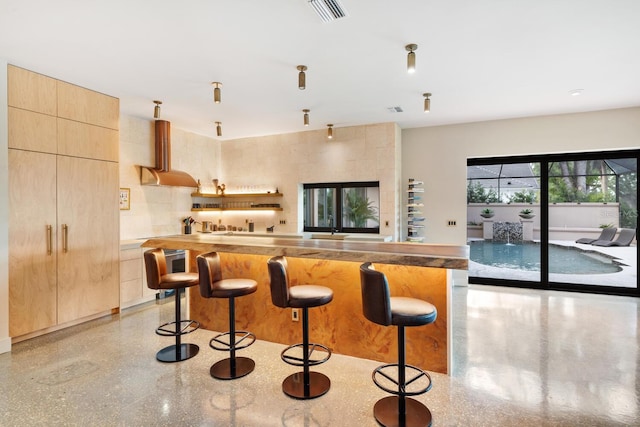 kitchen with visible vents, modern cabinets, open floor plan, a breakfast bar, and exhaust hood