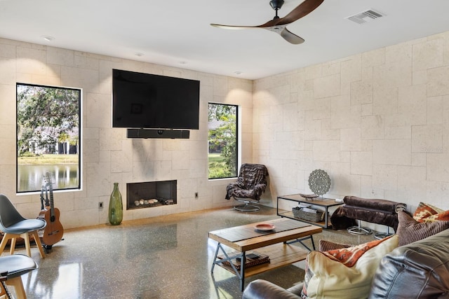 living area featuring speckled floor, visible vents, a fireplace, and ceiling fan