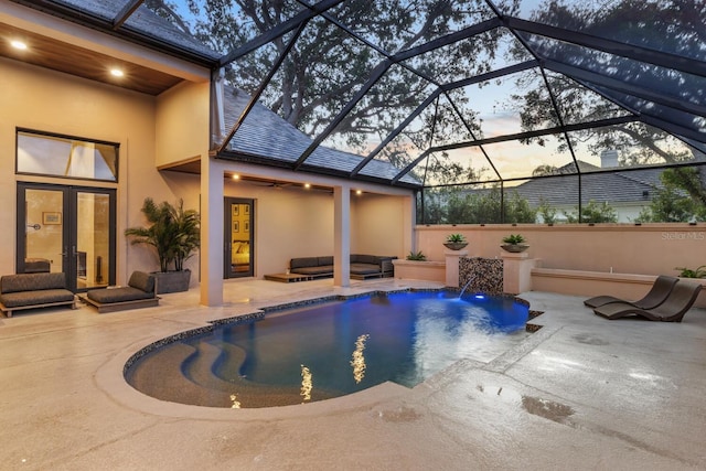 pool at dusk featuring an outdoor pool, ceiling fan, a lanai, a patio area, and outdoor lounge area