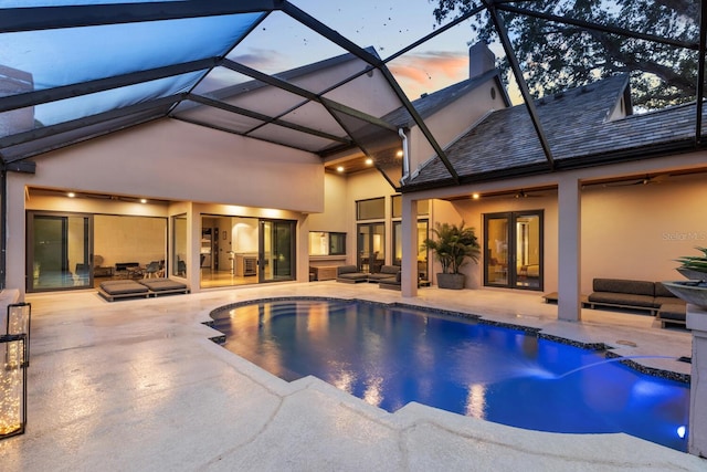 pool at dusk with ceiling fan, an outdoor pool, french doors, and a patio