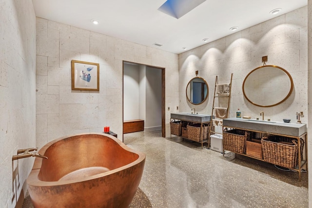 full bath featuring a sink, two vanities, a skylight, and a freestanding tub