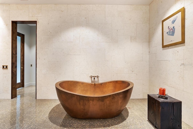 interior space featuring concrete block wall and a soaking tub