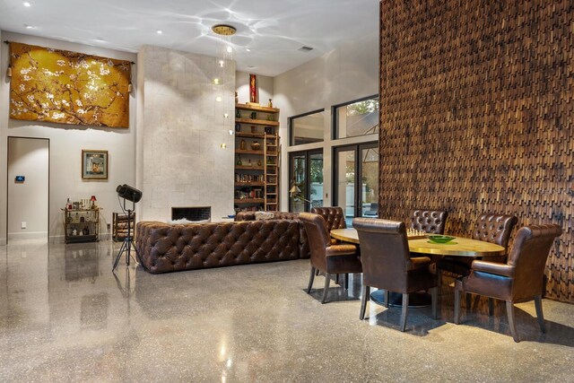 dining room with a high ceiling, a fireplace, and speckled floor