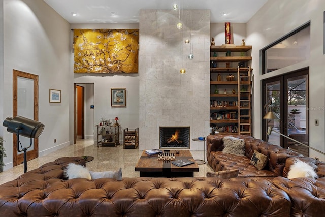 living area with french doors, a fireplace, a towering ceiling, and baseboards