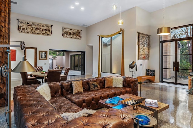 living room featuring a towering ceiling, baseboards, visible vents, and speckled floor