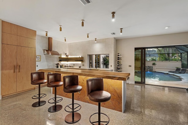 kitchen with a breakfast bar, visible vents, extractor fan, and speckled floor