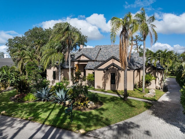 english style home with a front yard and stucco siding