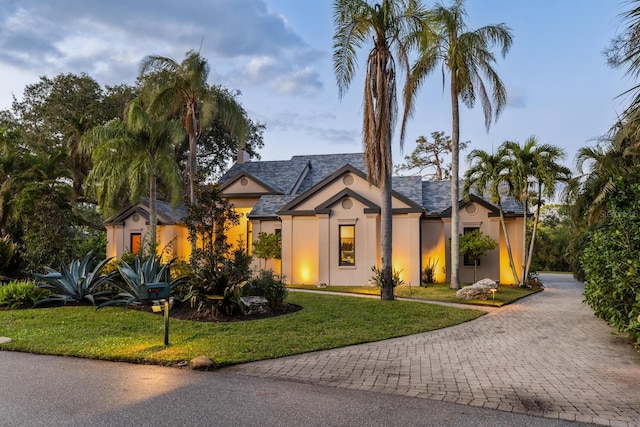 view of front of house with stucco siding, decorative driveway, and a front yard