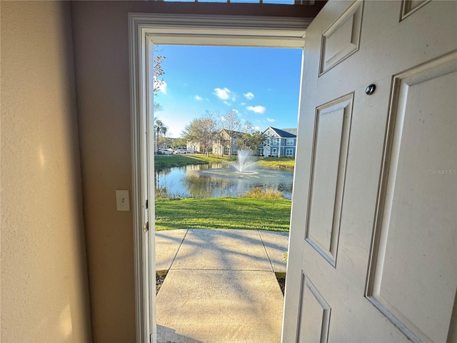 doorway to outside featuring a water view and a textured wall