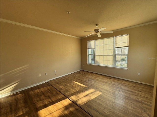 spare room with a ceiling fan, dark wood-style flooring, crown molding, and baseboards