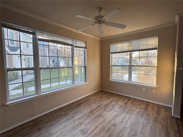 empty room with ornamental molding, ceiling fan, baseboards, and wood finished floors