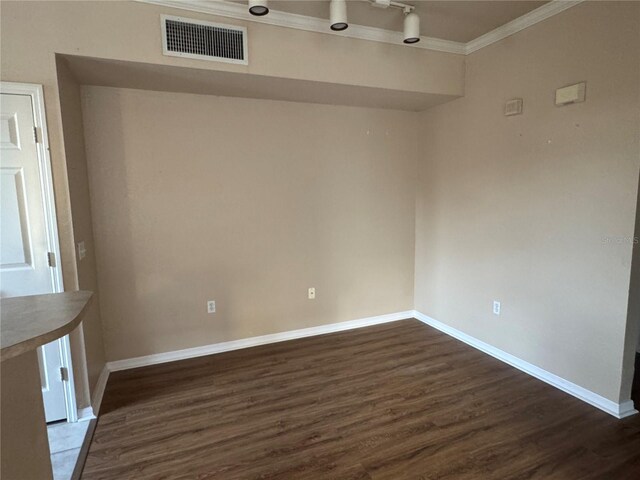 spare room featuring ornamental molding, dark wood-type flooring, visible vents, and baseboards