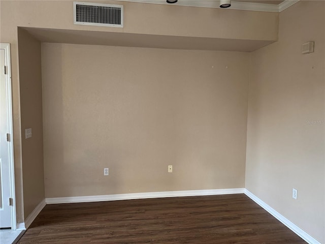 spare room with dark wood-type flooring, visible vents, and baseboards