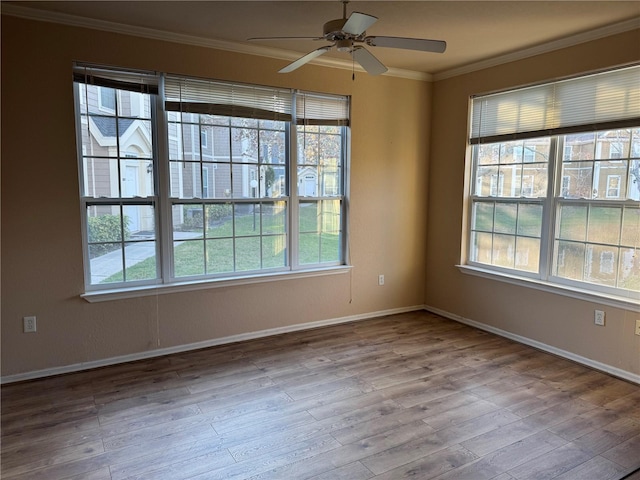 empty room featuring baseboards, wood finished floors, and crown molding