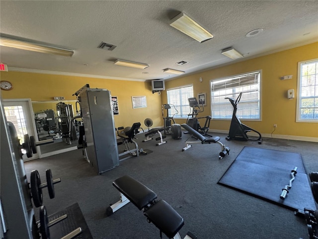 gym with a textured ceiling, baseboards, visible vents, and a healthy amount of sunlight