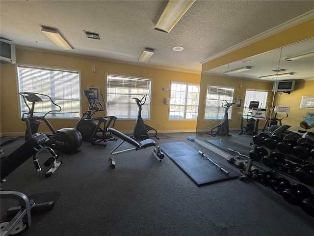 workout area featuring a textured ceiling, baseboards, visible vents, and crown molding