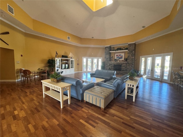 living room with a fireplace, a towering ceiling, visible vents, a healthy amount of sunlight, and french doors