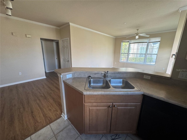 kitchen featuring crown molding, a sink, a peninsula, and light tile patterned floors