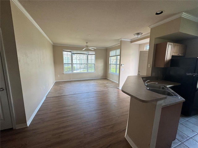 kitchen with crown molding, dark wood-type flooring, freestanding refrigerator, open floor plan, and a peninsula