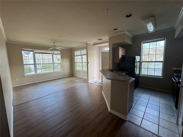 kitchen featuring wood finished floors, open floor plan, freestanding refrigerator, dark countertops, and crown molding