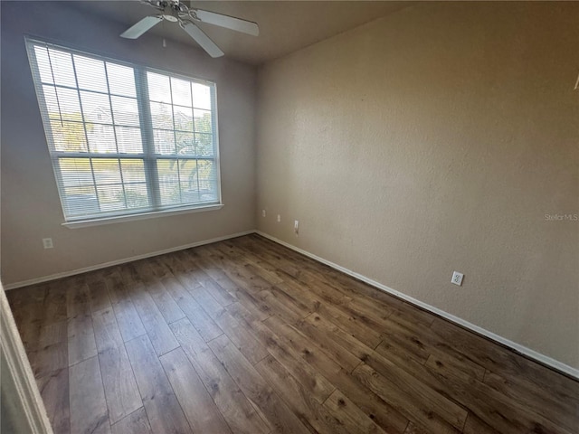 unfurnished room with baseboards, a ceiling fan, and dark wood-type flooring