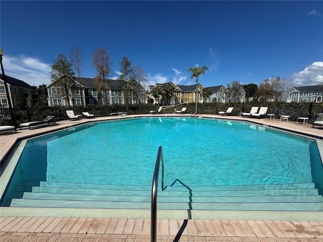 community pool featuring a patio area, a residential view, and fence