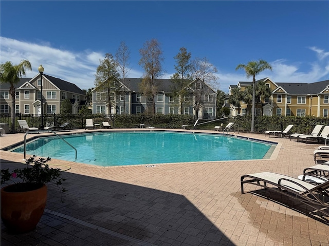 pool with a residential view, a patio area, and fence